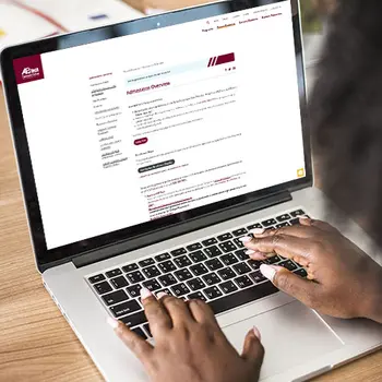Persons hands typing on a laptop.