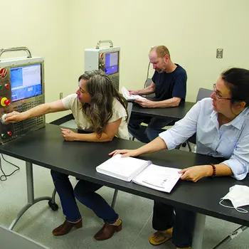 Students setting at a desk looking at a machine