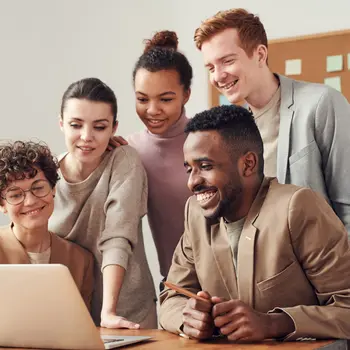 A group of smiling people looking at a laptop
