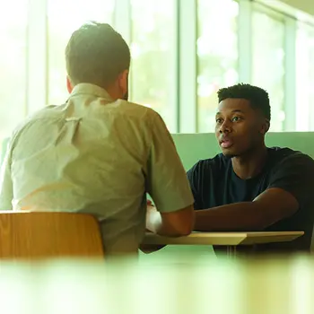 Two men sitting at a table talking