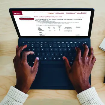 Image of two hands typing on a laptop