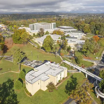 An aerial view of a college campus with trees and mountains