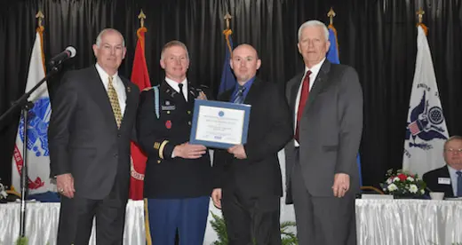Four men in uniform on a stage