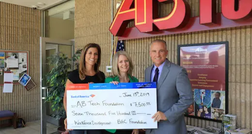 Three people holding an oversized check