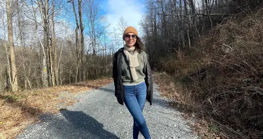 Woman in jacket and hat standing on a trail