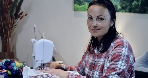 Nataliia Chorna sitting at sewing machine