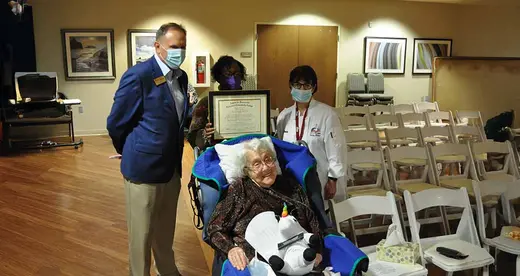 A woman in a wheelchair with 3 people standing behind her. 