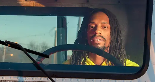 Man wearing yellow shirt sitting in the cab of a truck