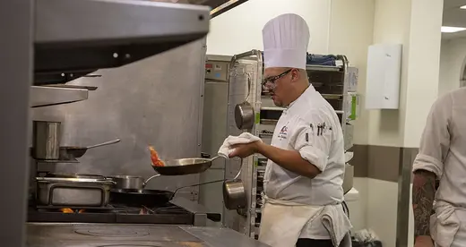 Chef with frying pan in front of stove