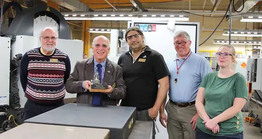 Dennis King holding a miniature engine lathe with 4 other people