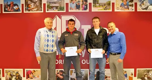 Gentry Heating President and three Gentry Heating Scholarship recipients standing in front of a wall