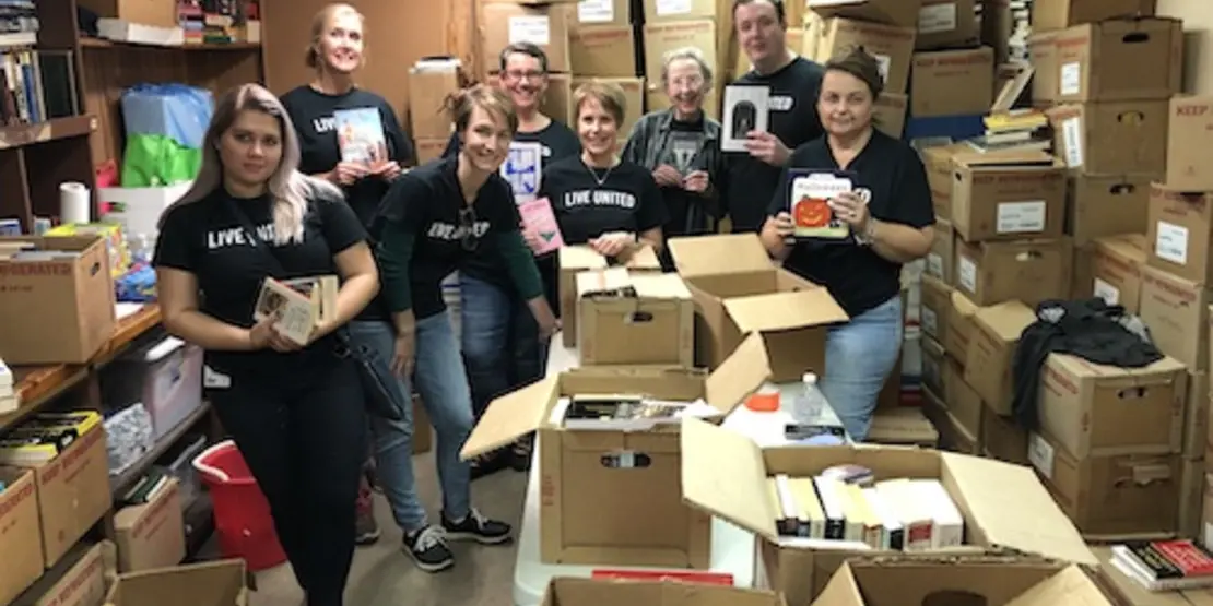 People surrounded by boxes of books