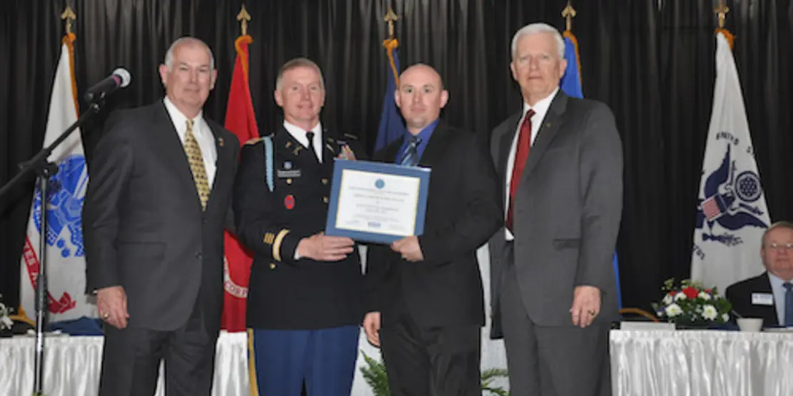 Four men in uniform on a stage