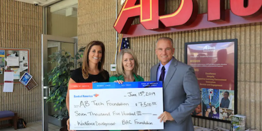 Three people holding an oversized check