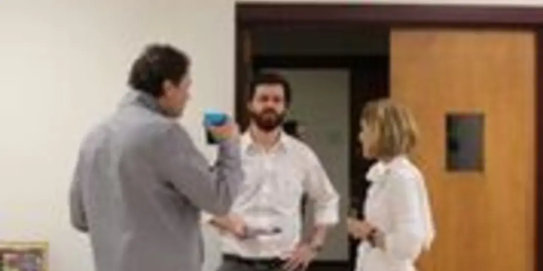 Three people standing and talking to one another.