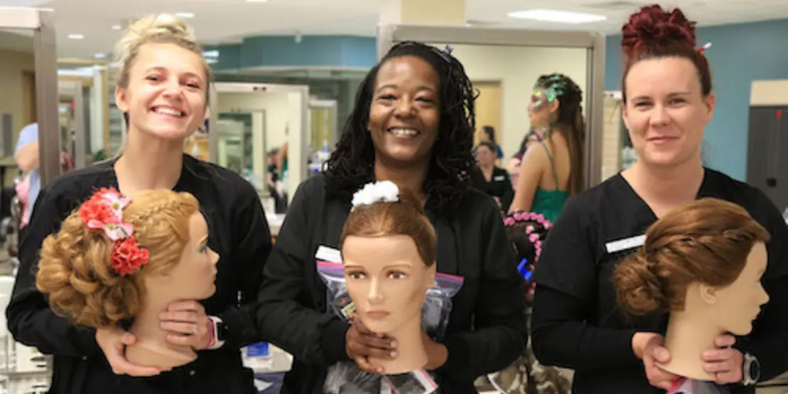 Cosmetology students holding mannequins