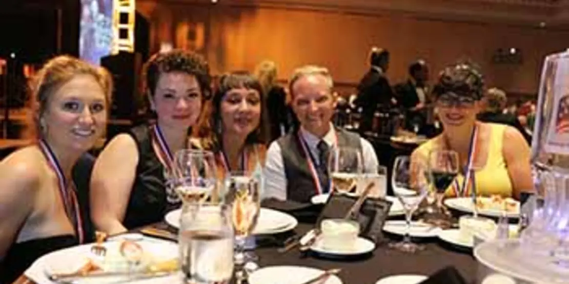 Five chefs wearing bronze medals at a table.