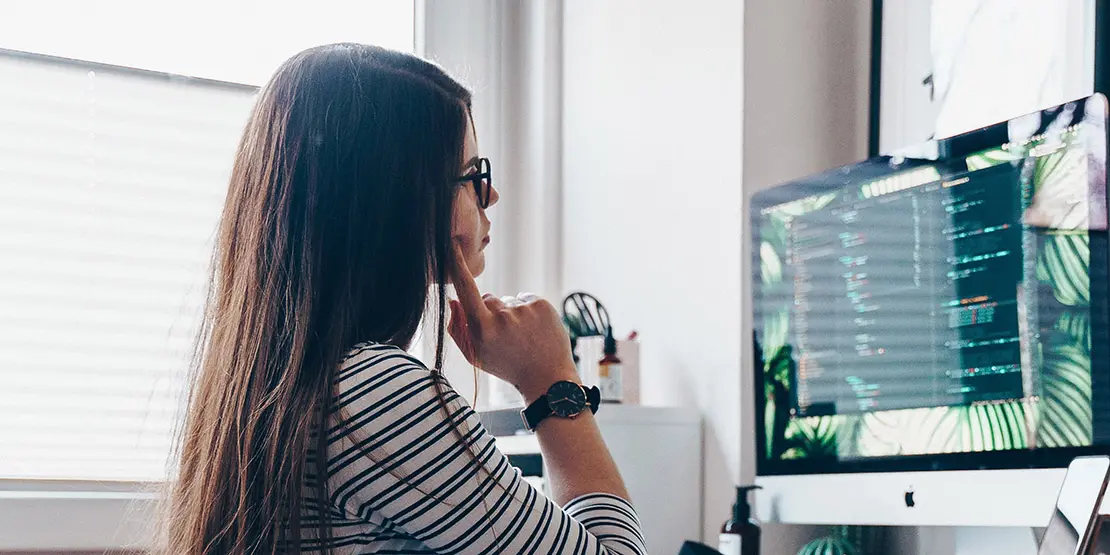 Female student sitting at a desk doing their studies using a computer online