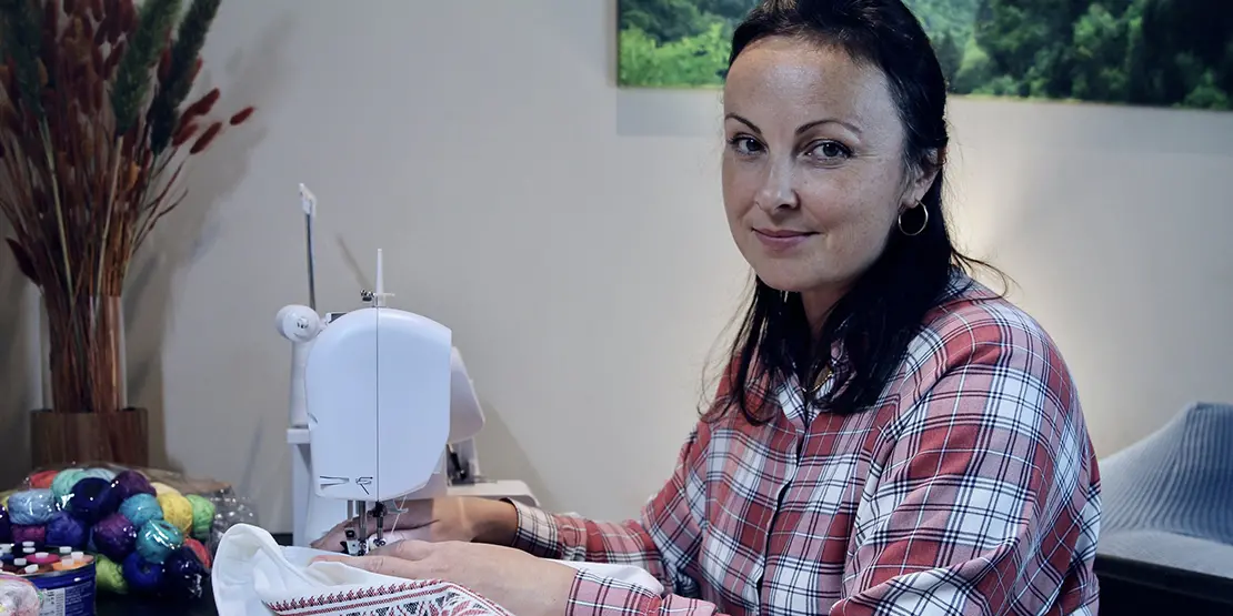 Nataliia Chorna sitting at sewing machine