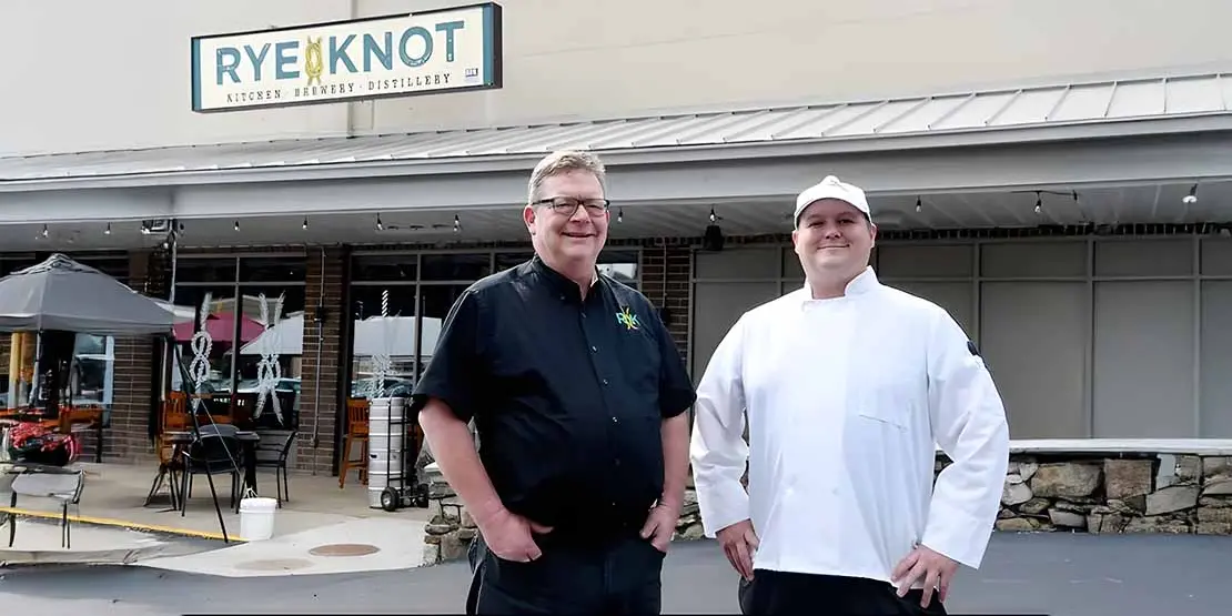 Man and chef in front of distillery