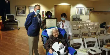 A woman in a wheelchair with 3 people standing behind her. 