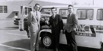 Three men in front of a radio broadcasting van