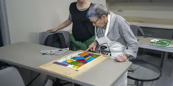 Older woman with stained glass project on table